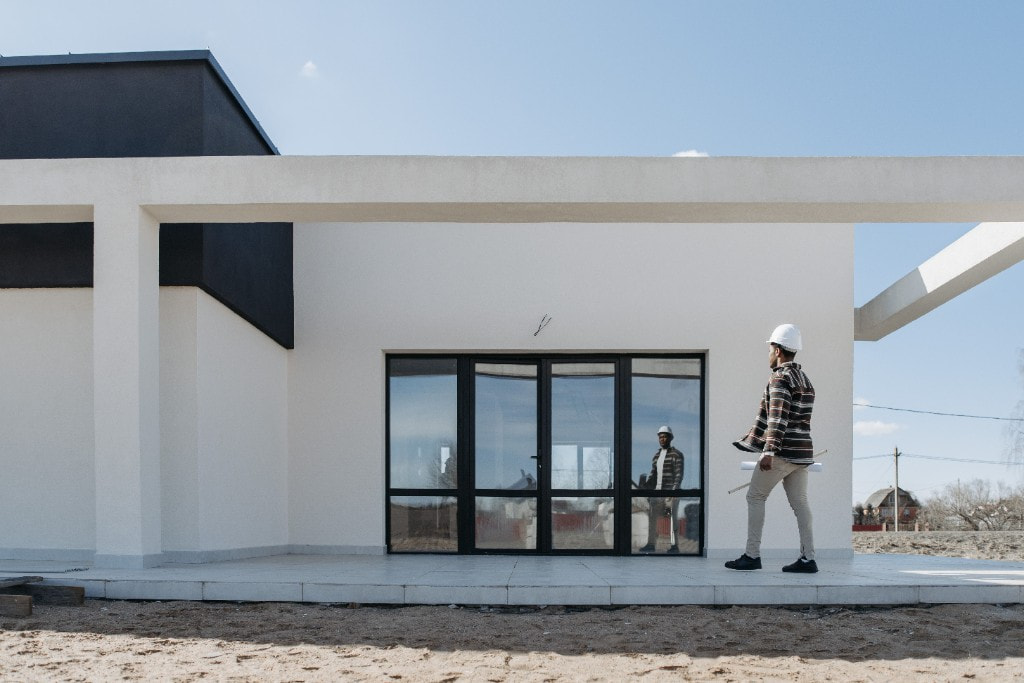 Architect met helm en bouwplannen bij een moderne woning